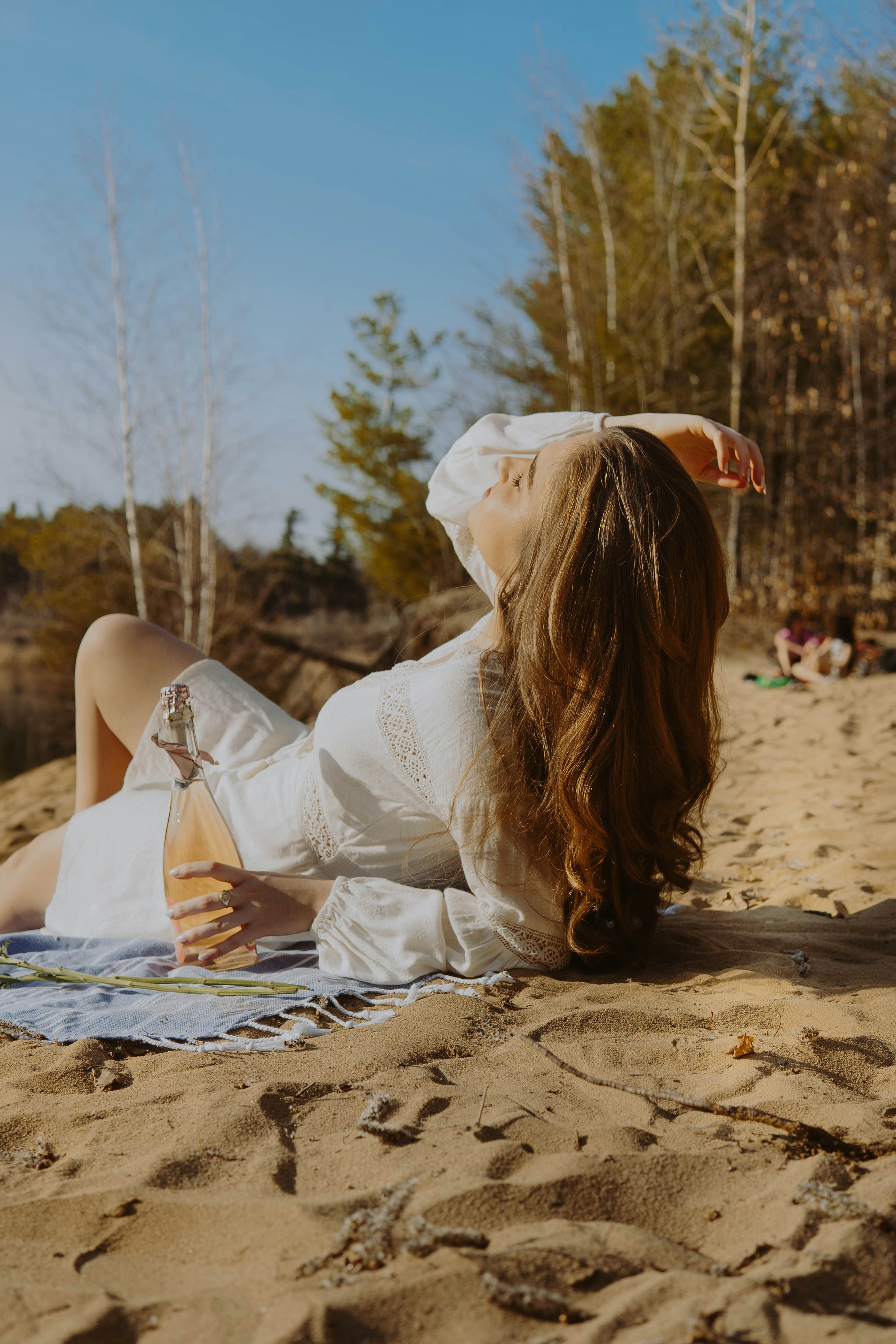 woman in white dress lying on sand during daytime